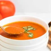 一勺新鲜煮熟的番茄汤在一个白色的碗里。gydF4y2Ba